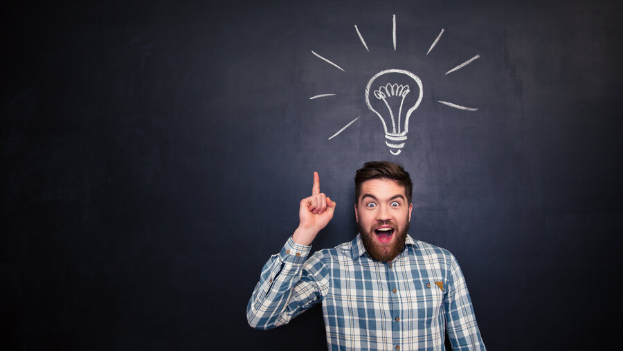 Excited man pointing up over blackboard background with light bulb Excited man pointing up over blackboard background with light bulb