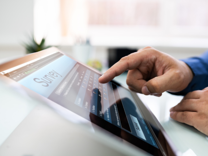 Eine Hand tippt auf einem iPad, auf dem eine Umfrage geöffnet ist