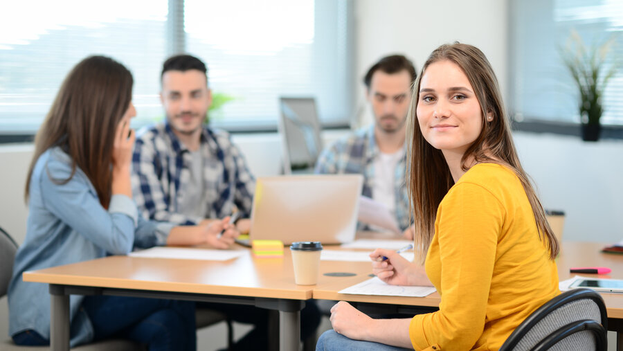 portrait of young woman in casual wear working in creative business startup company office with coworker people in background