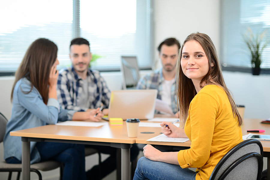 portrait of young woman in casual wear working in creative business startup company office with coworker people in background